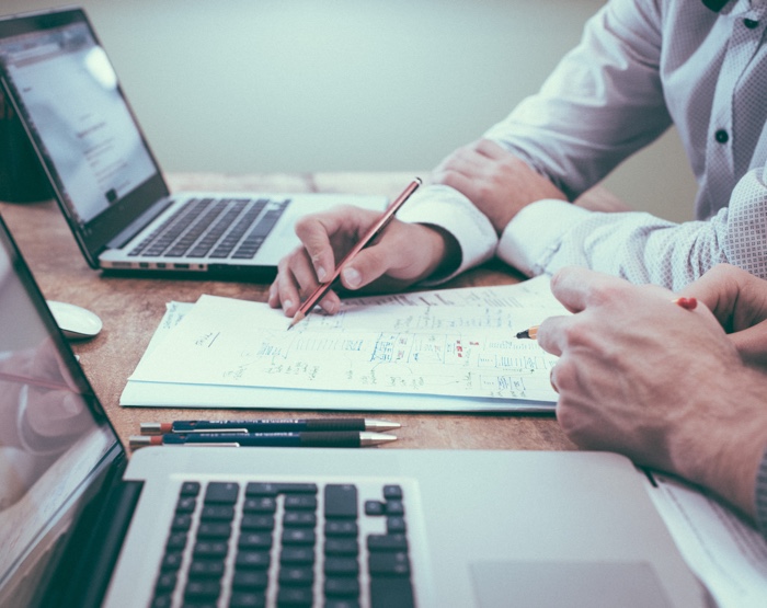 Two men writing blockchain solutions on a sheet of paper